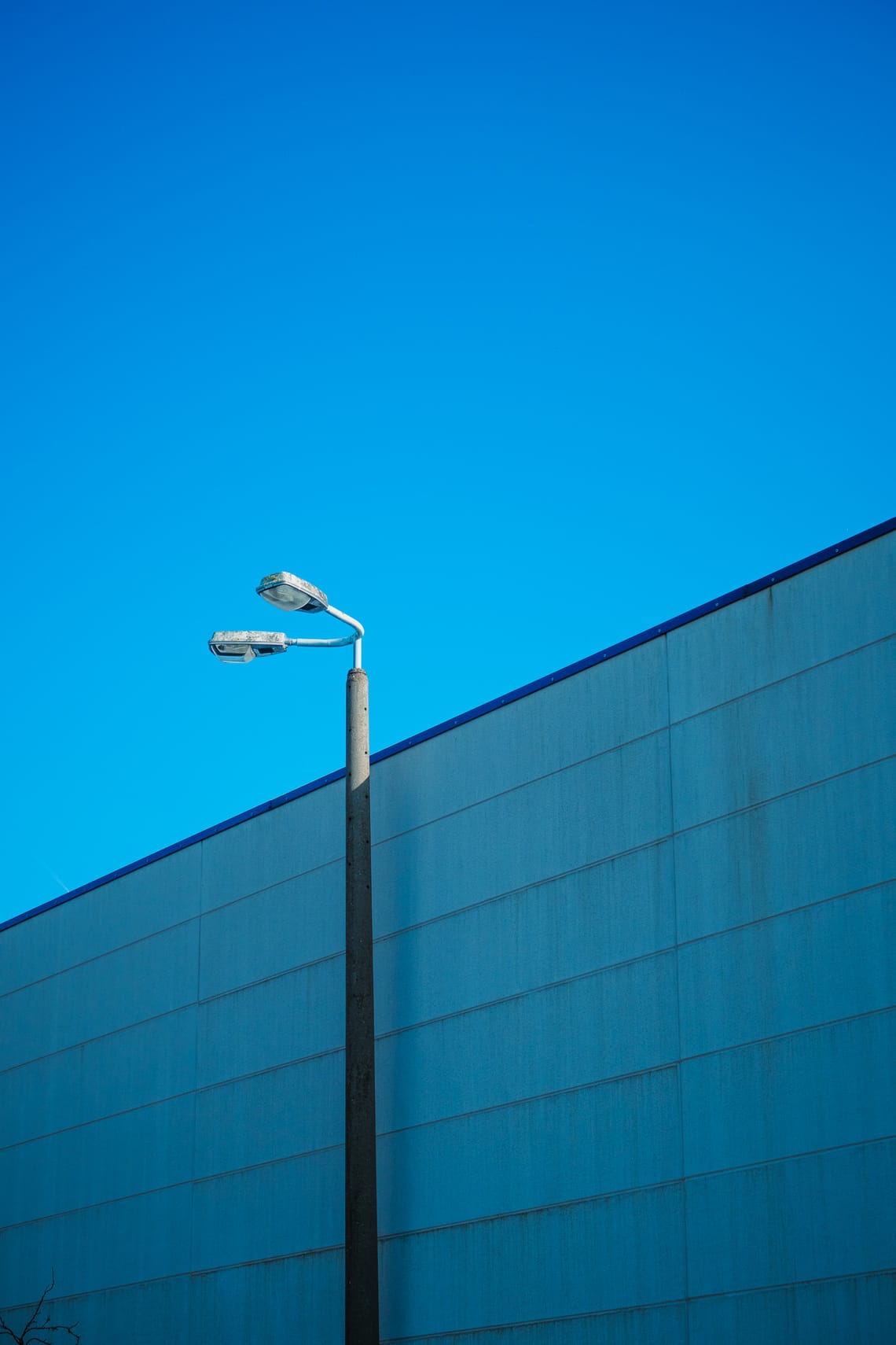 Eine Laterne vor einer Mauer und blauem Himmel.