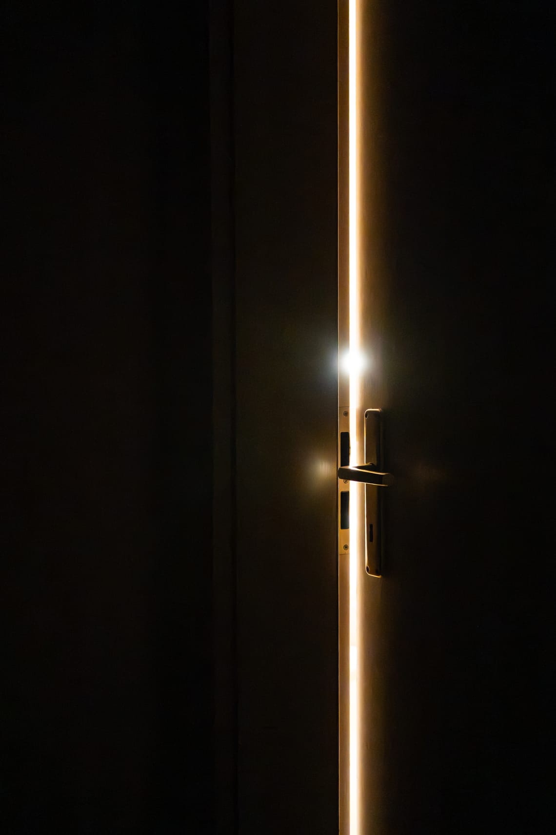 Lichtspalt einer angelehnten Tür im Dunkeln.